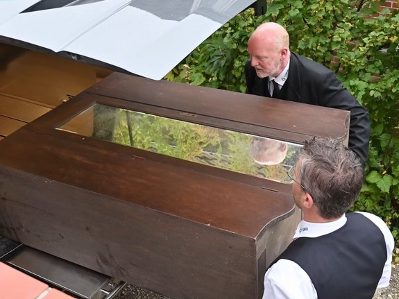 2 Herren schieben einen Sarg in einen Kofferraum