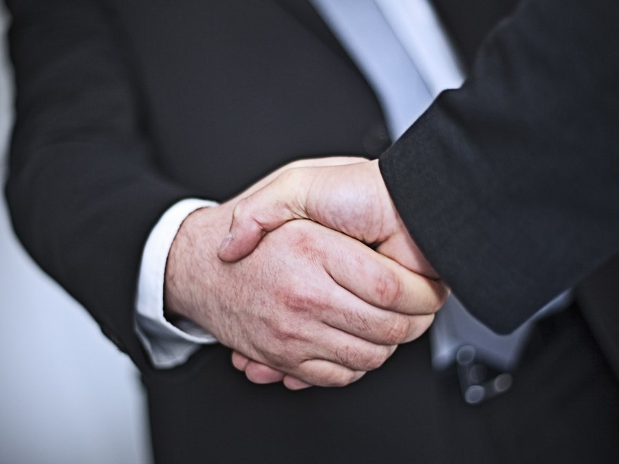 Es geben sich zwei Männer im Anzug die Hand. 