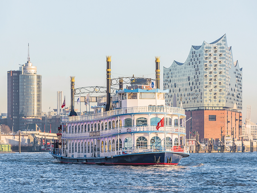 Auf dem Wasser ist ein Dampfer von Rainer Abicht. Im Hintergrund erkennt man die Skyline von Hamburg mit dem Gebäude der Elbphilharmonie. 