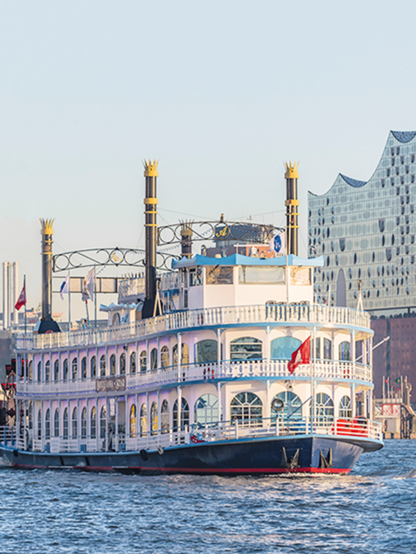Auf dem Wasser ist ein Dampfer von Rainer Abicht. Im Hintergrund erkennt man die Skyline von Hamburg mit dem Gebäude der Elbphilharmonie. 