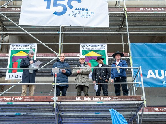 (v.l.n.r.) Gregor Bunde (coop eG), Franz-Josef Höing (Baudirektor), Frank Seeger (dhu), Eduard Schneider (Aug.Prien) und Thomas Joost (Aug.Prien) stehen auf dem Baugerüst vor dem Rohbau.