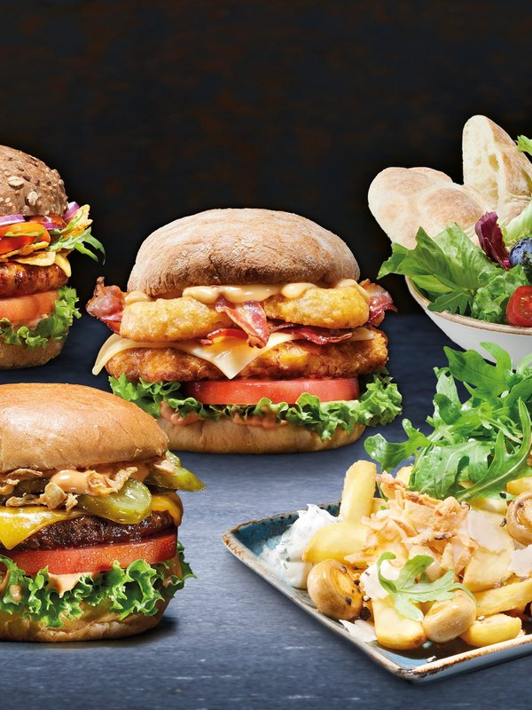 Auf dem Bild links sind 3 Burger, rechts oben davon ein Salat in einer Schale, darunter ein Teller mit Pommes