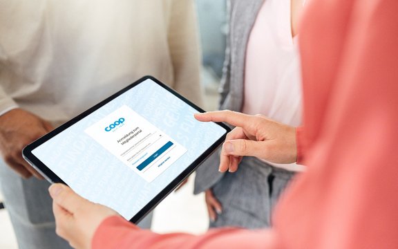 Hände halten ein Tablet, das die Login-Seite des Mitgliederportals zeigt