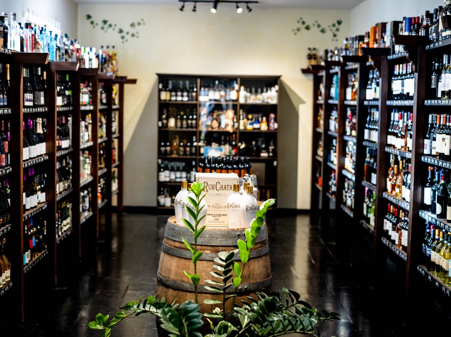 In der Mitte ist ein Eichenfass. Um das Fass herum sind dunkle Holzregale, die mit Weinflaschen gefüllt sind. 