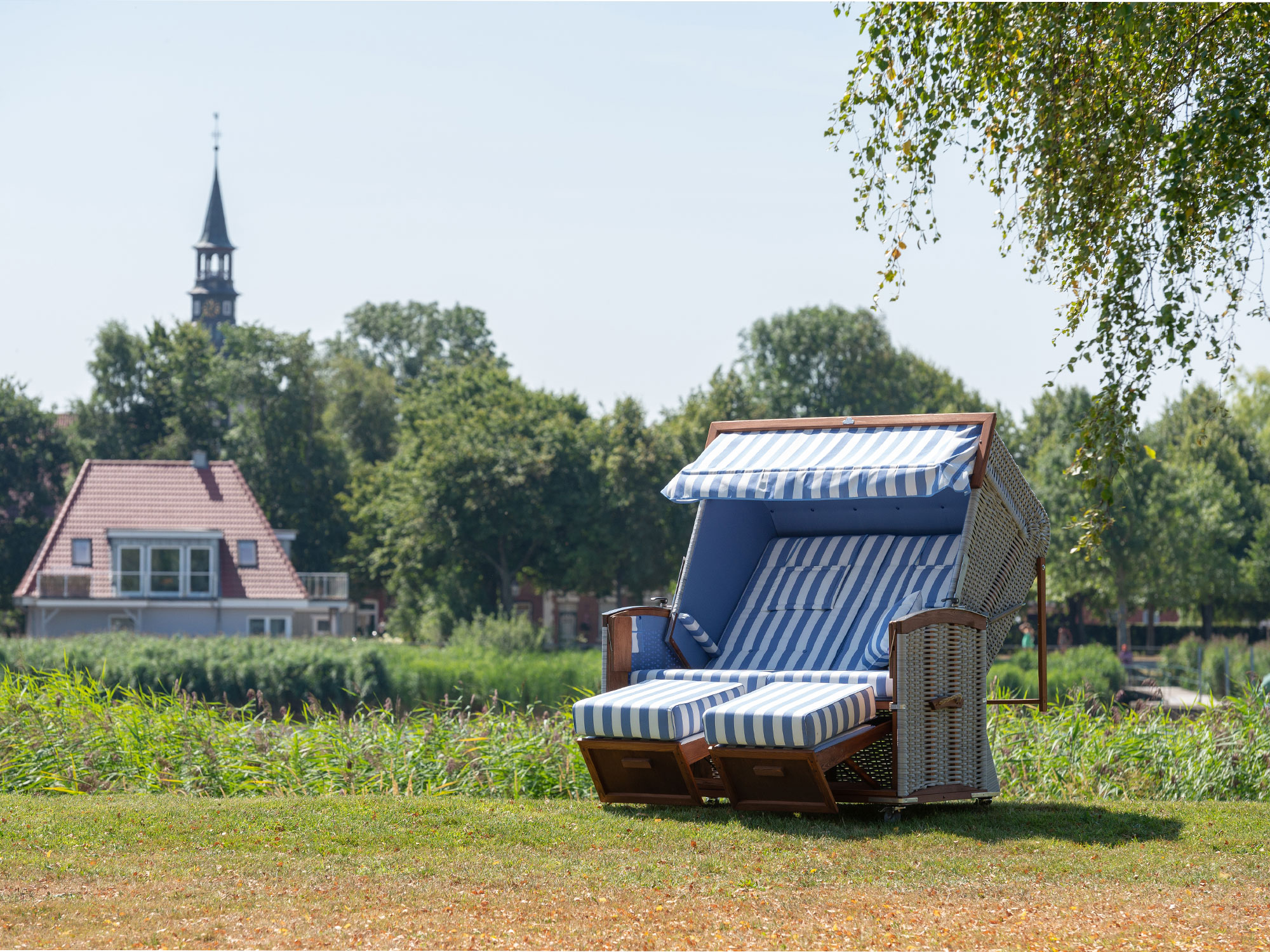 Ein Strandkorb steht in grüner Landschaft und bei Sonnenschein in der Natur