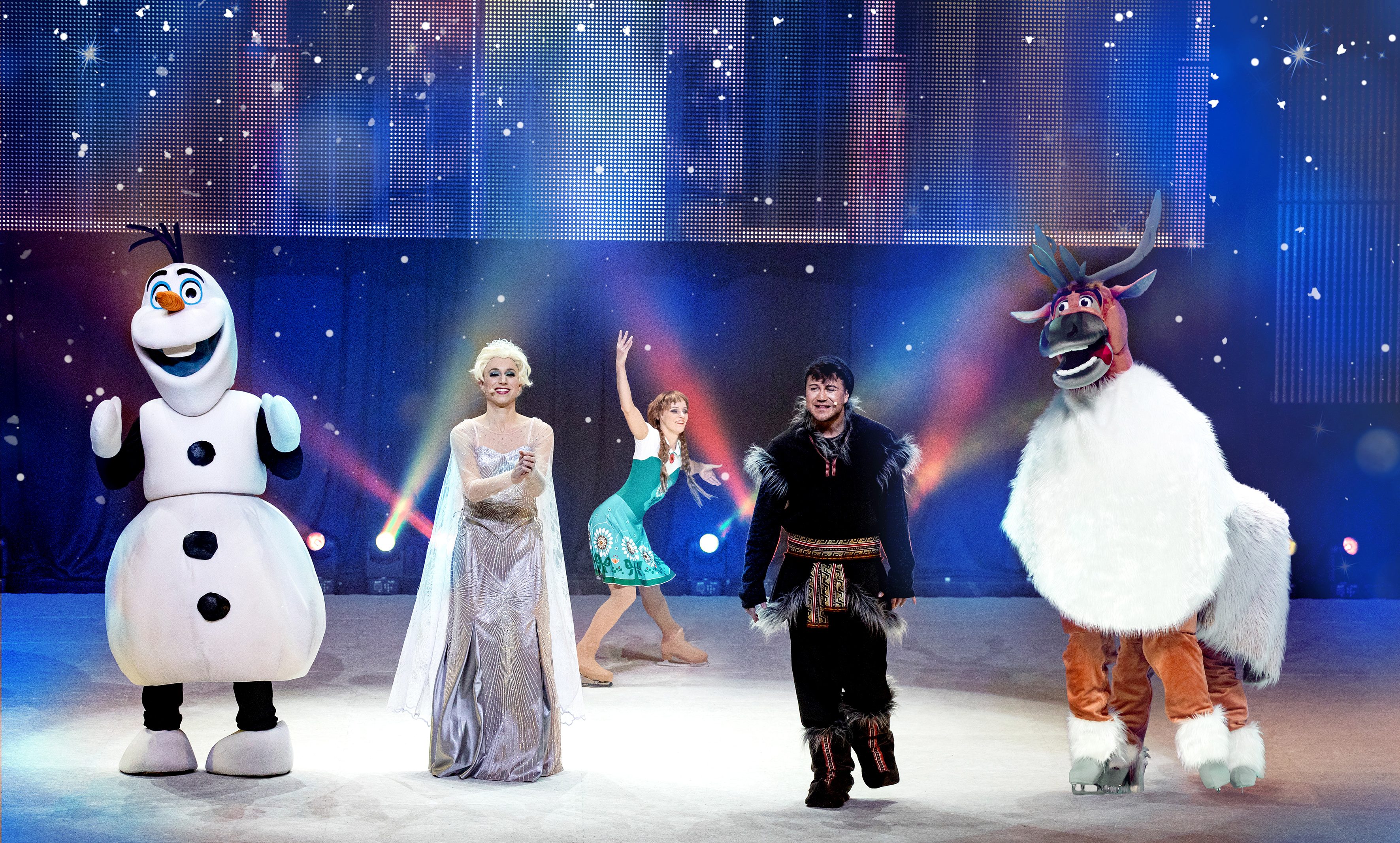 Blauer Hintergrund, im Vordergrund die Darsteller auf der Bühne, von links Olaf der Schneemann, daneben die Eiskönigin, daneben Christoph und ganz rechts das Rentier Sven